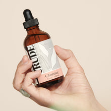 Load image into Gallery viewer, A hand holding a 4 oz bottle of CRUDE Cleanse